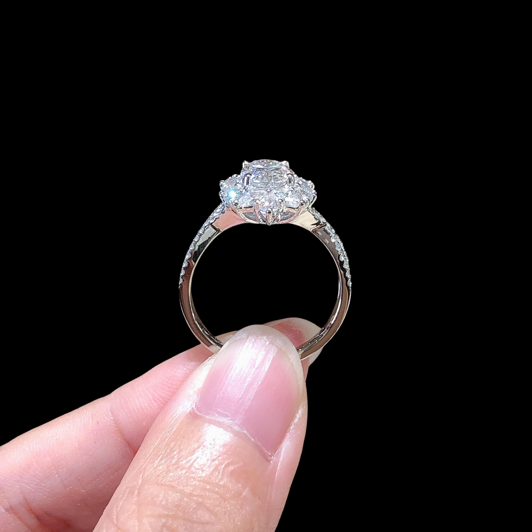 Diamond ring held between fingers against a black background