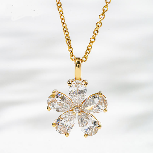 Gold necklace with a four-leaf clover-shaped diamond pendant on a light gray background