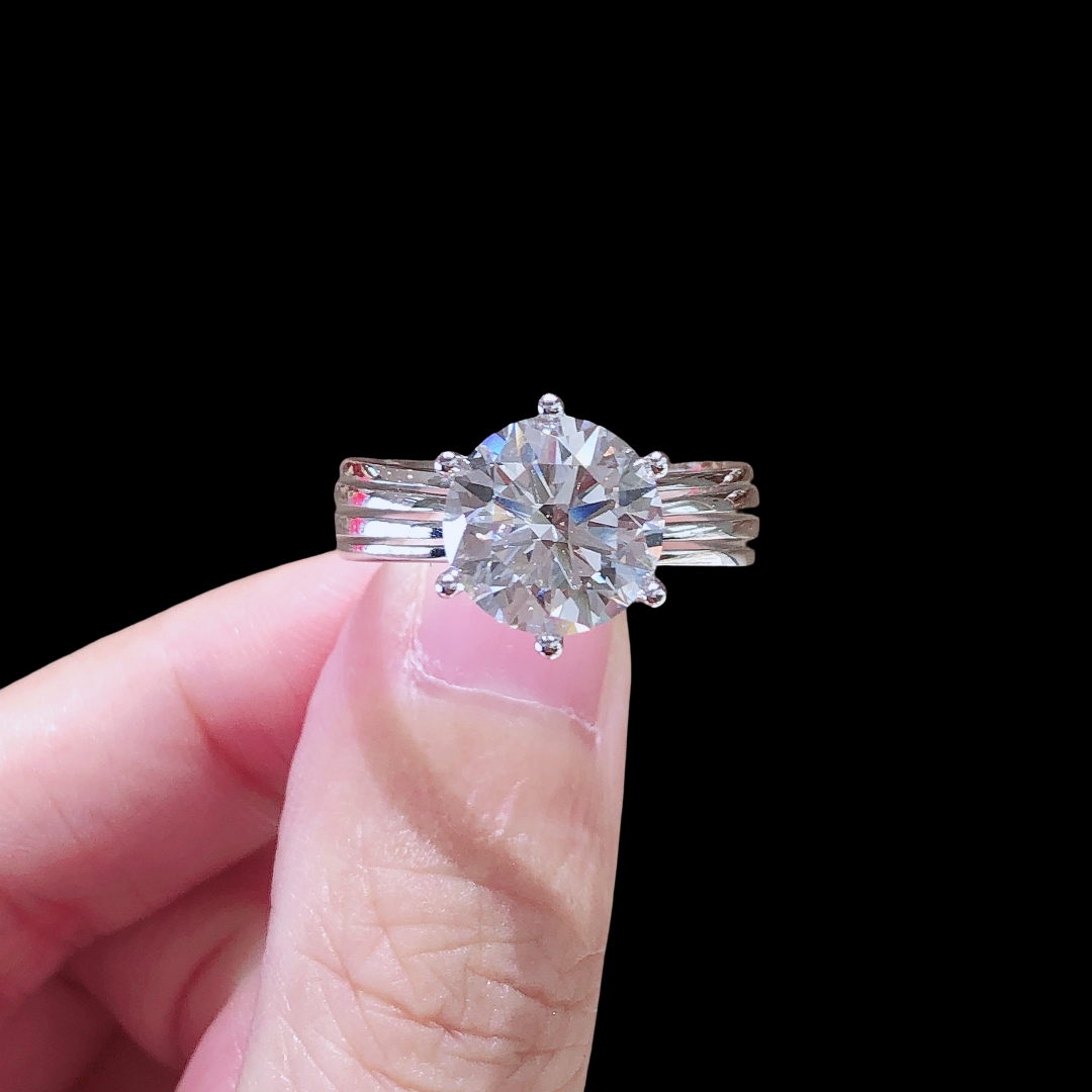 Diamond ring held between fingers against a black background