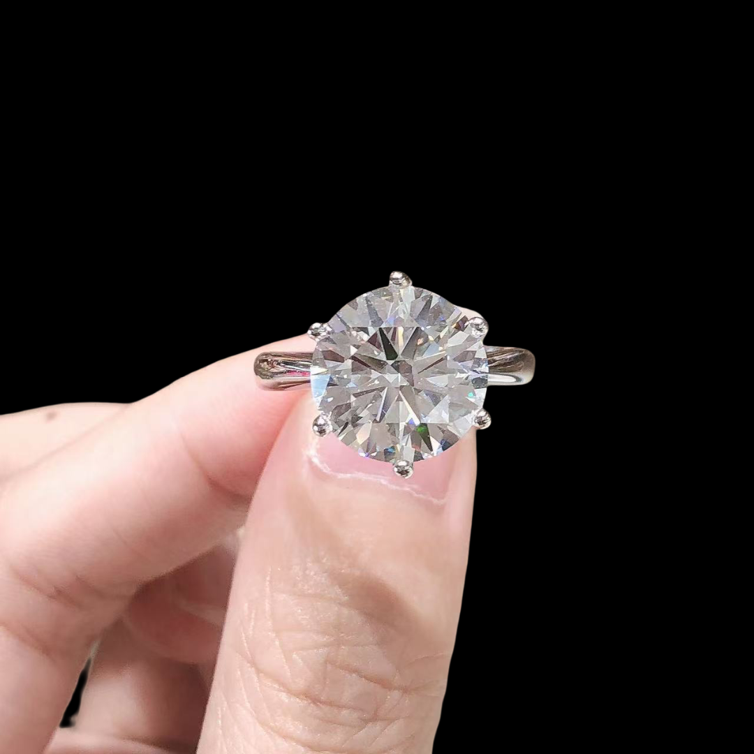 Diamond ring held between fingers against a black background