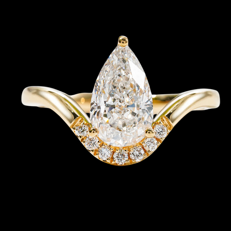 Gold ring with a pear-shaped diamond and smaller diamonds on a black background