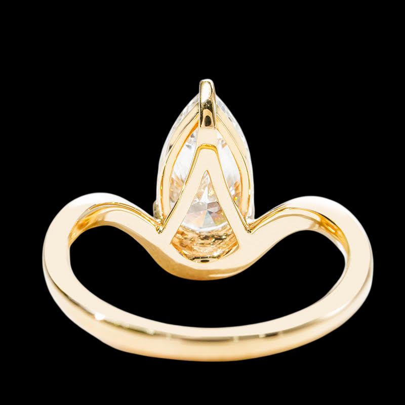 Gold ring with a pear-shaped diamond on a black background