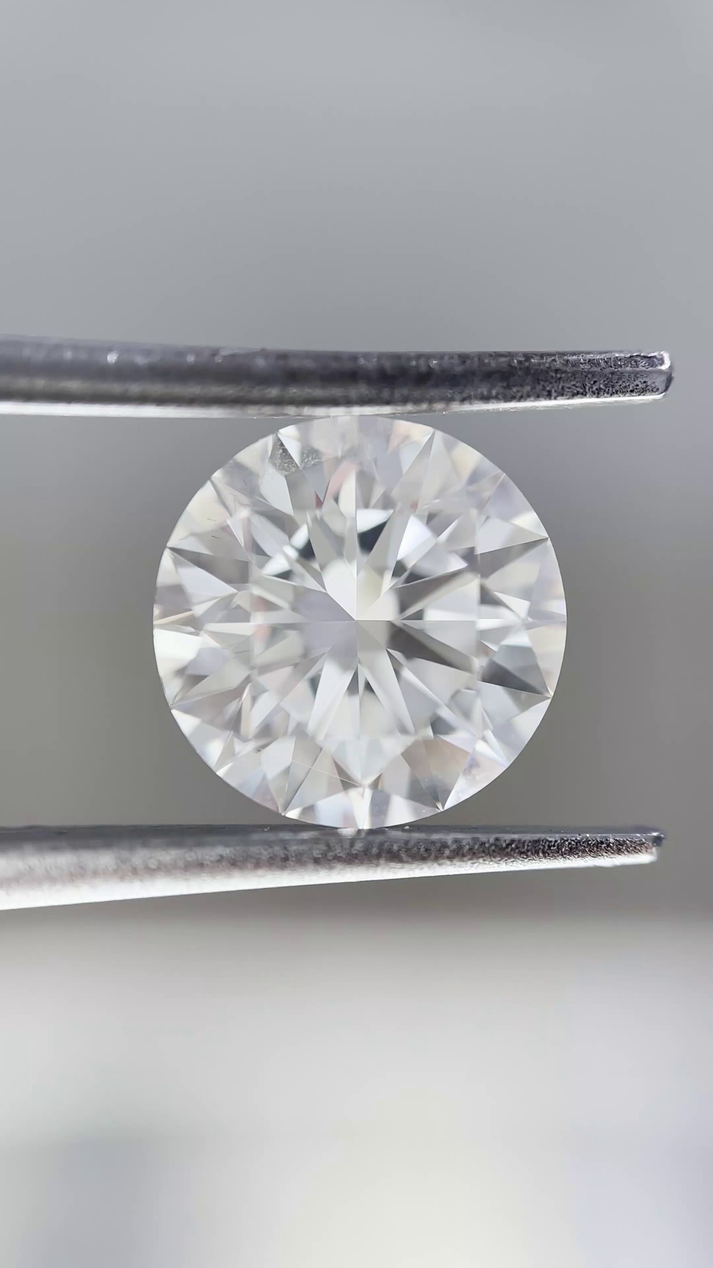 Diamond held between tweezers against a neutral background