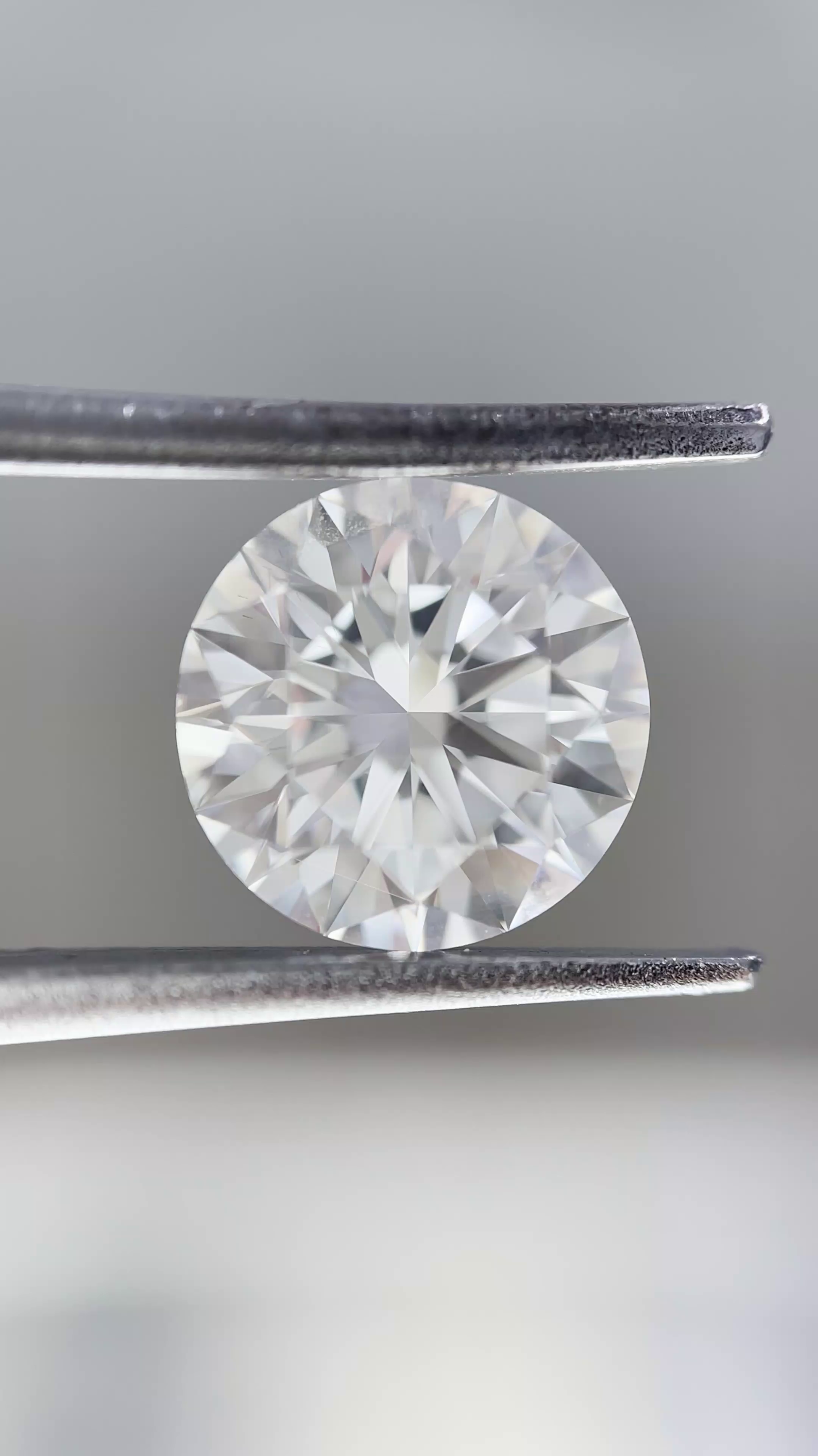 Diamond held between tweezers against a neutral background