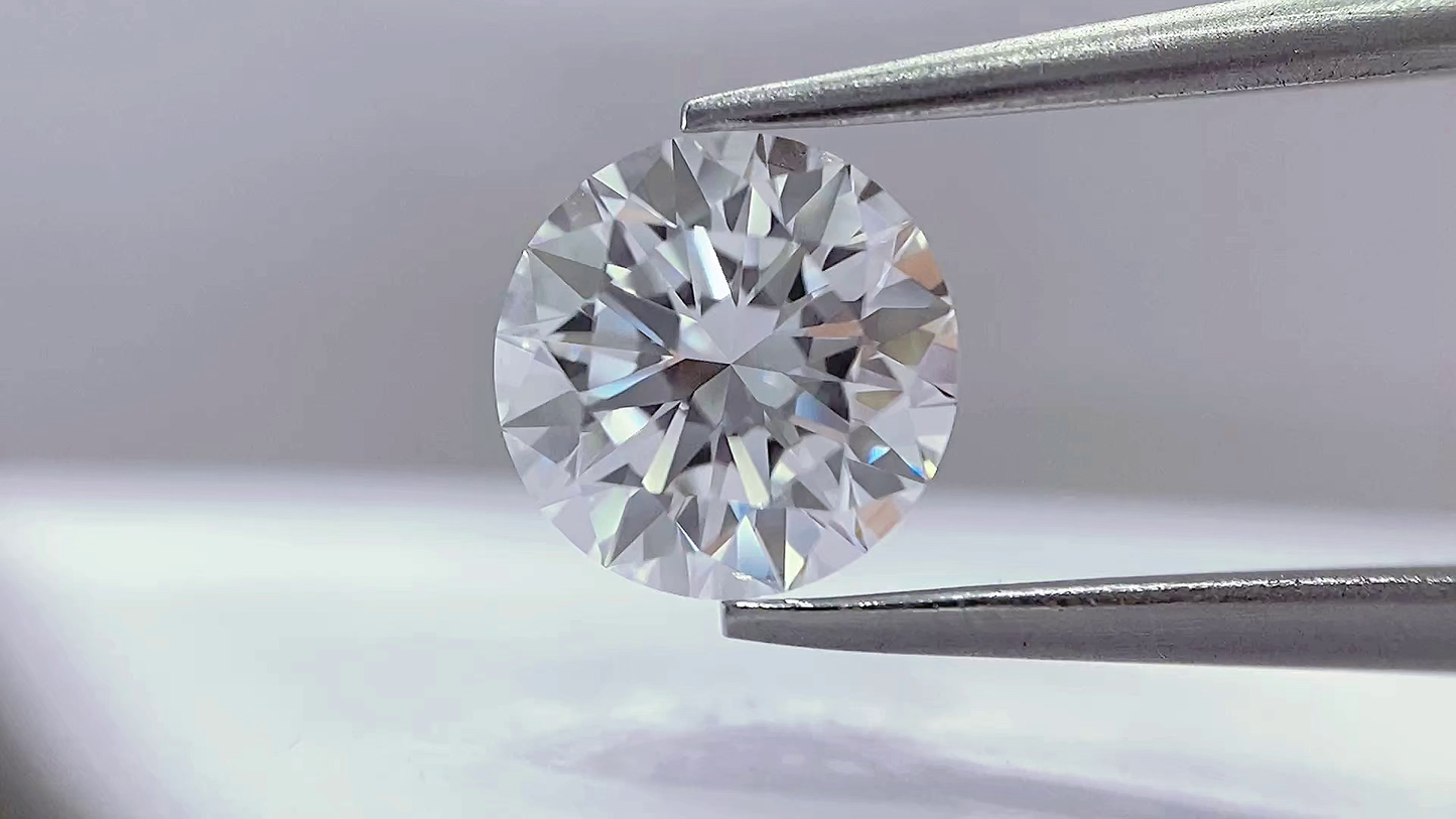 Round diamond held by tweezers against a neutral background