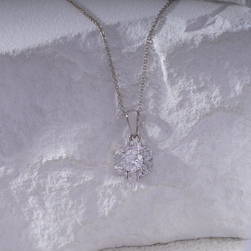 Silver necklace with a snowflake pendant on a textured white surface