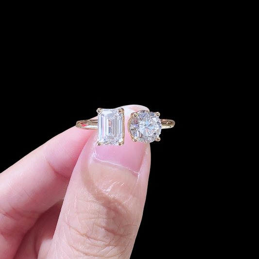 Two diamond rings held between fingers against a black background