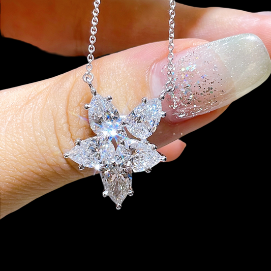Diamond necklace held by a hand against a black background