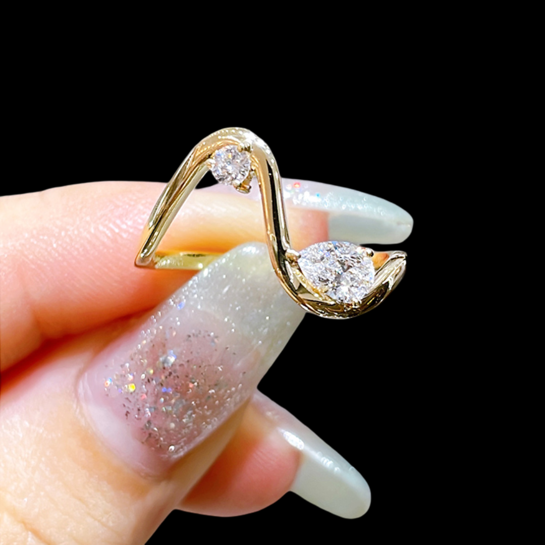 Gold ring with diamonds held by a hand with glittery nail polish on a black background