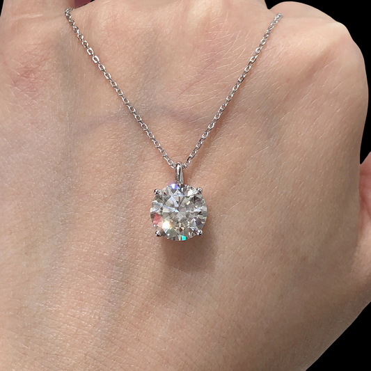 Diamond necklace on a hand against a neutral background