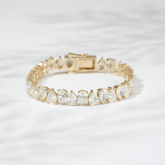 Gold bracelet with clear gemstones on a light gray background