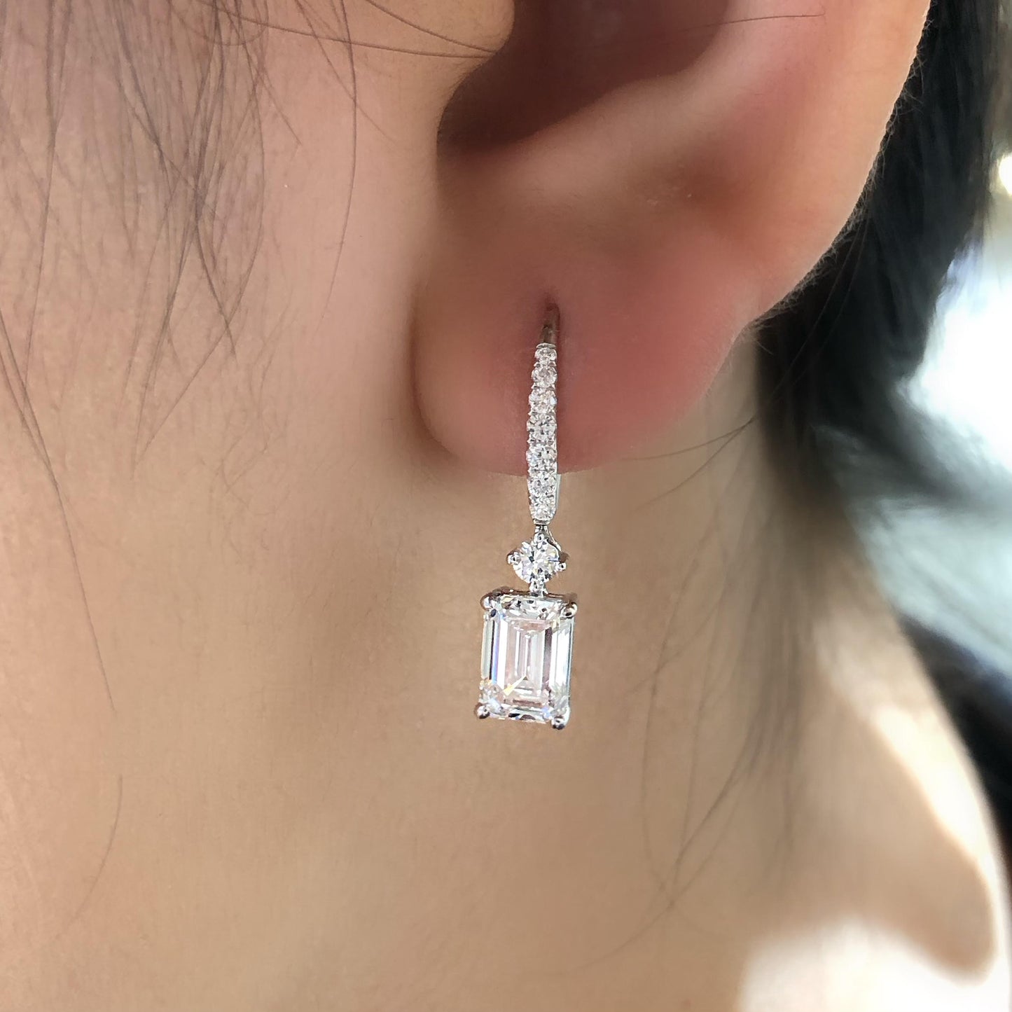 Diamond earring worn on an ear with a blurred background