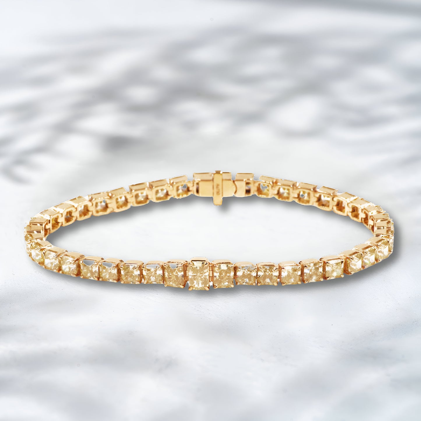 Gold bracelet with square-cut stones on a light gray background