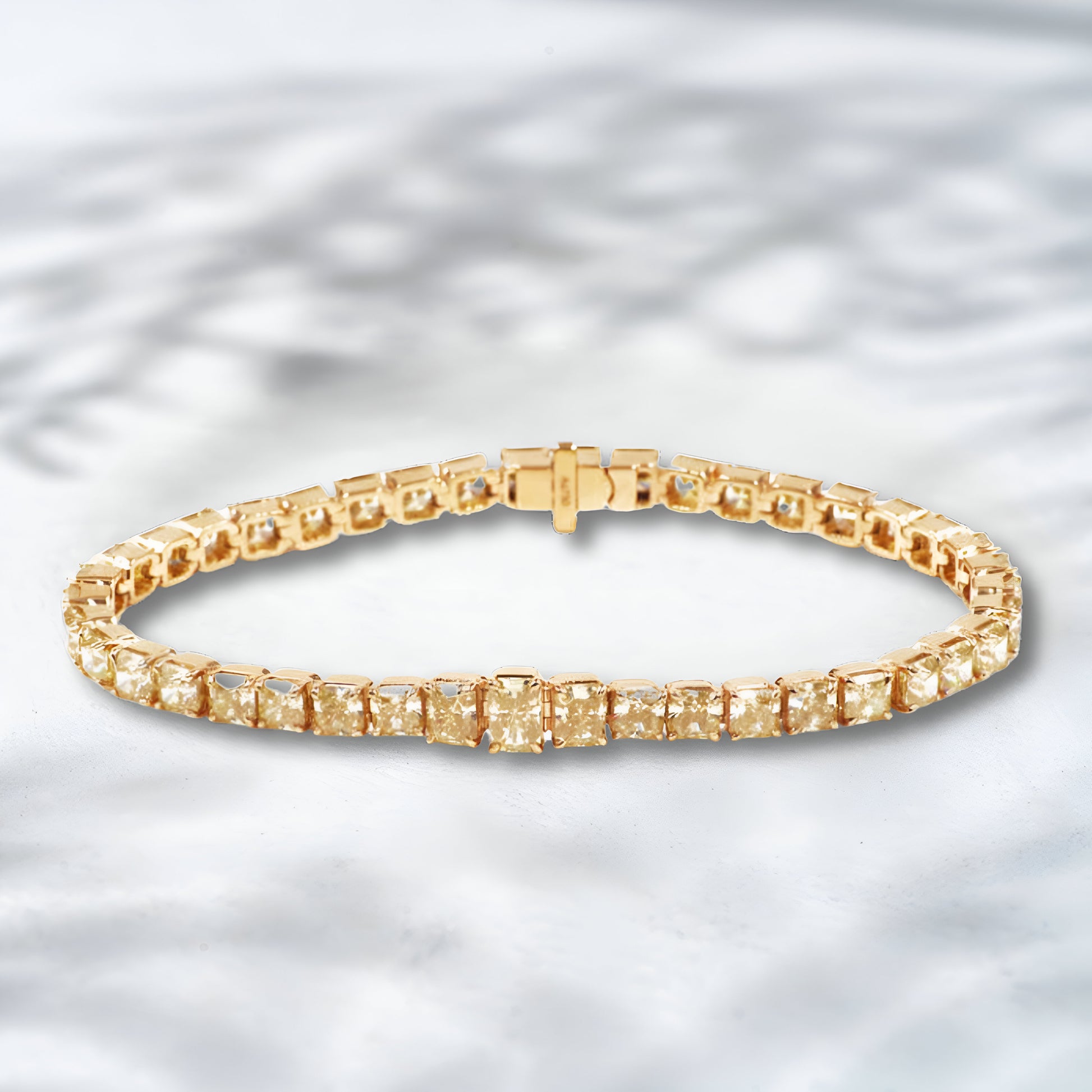 Gold bracelet with square-cut stones on a light gray background