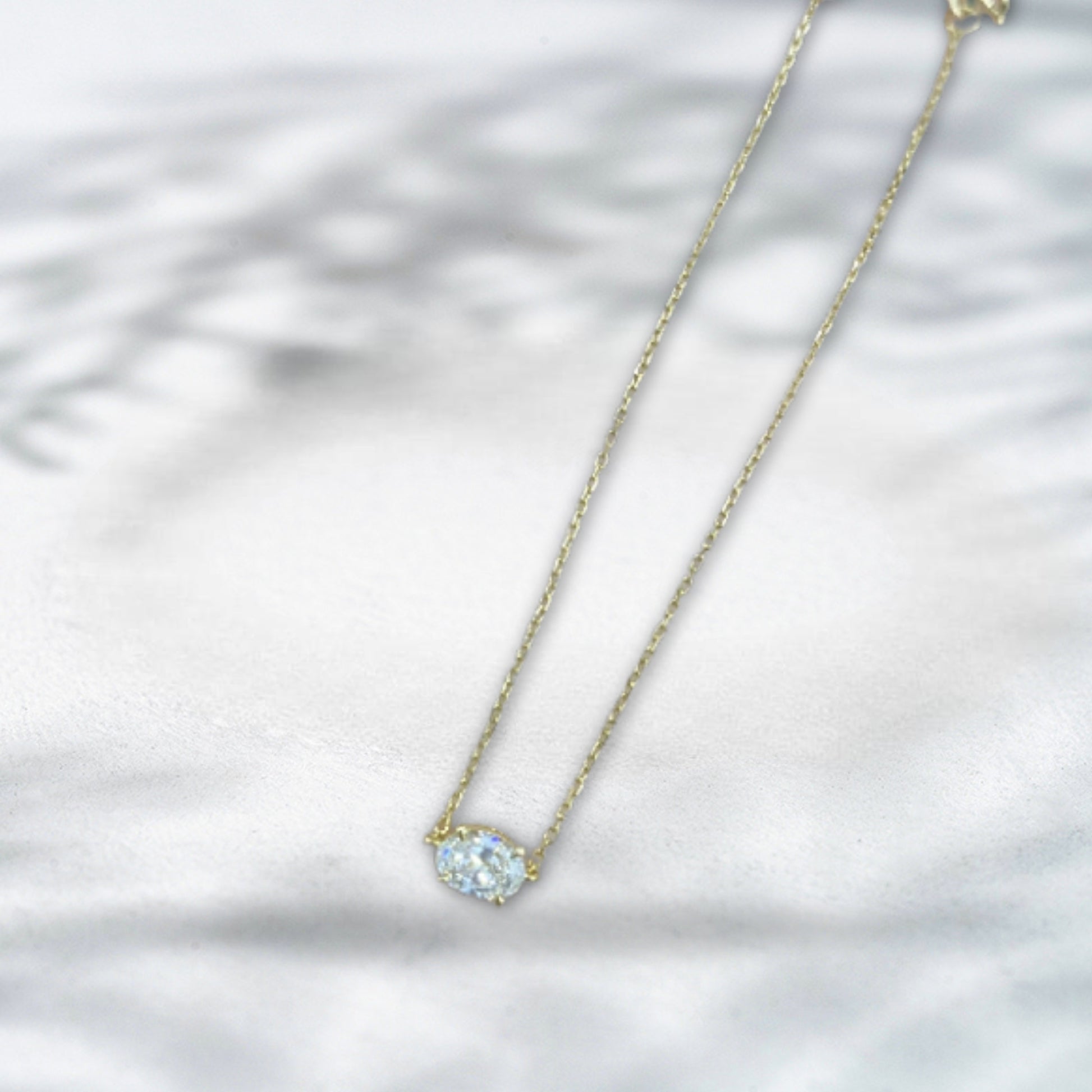 Gold necklace with a clear gemstone on a white background