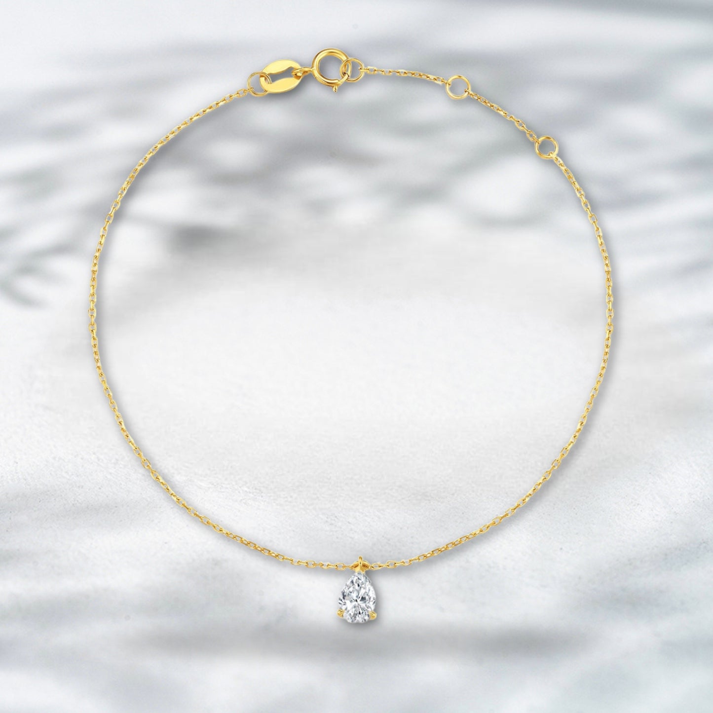 Gold bracelet with a diamond on a soft gray background