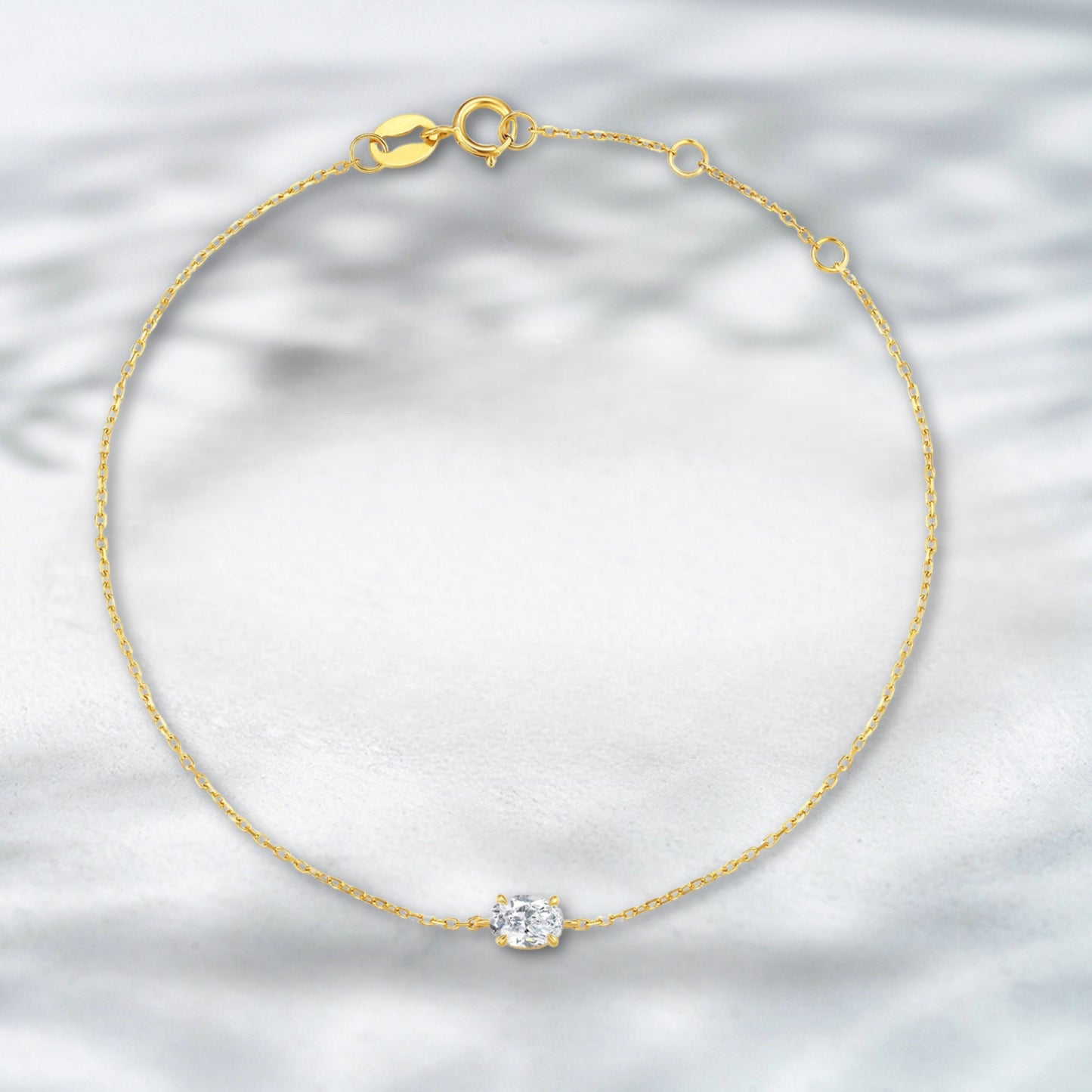 Gold bracelet with a diamond on a light gray background