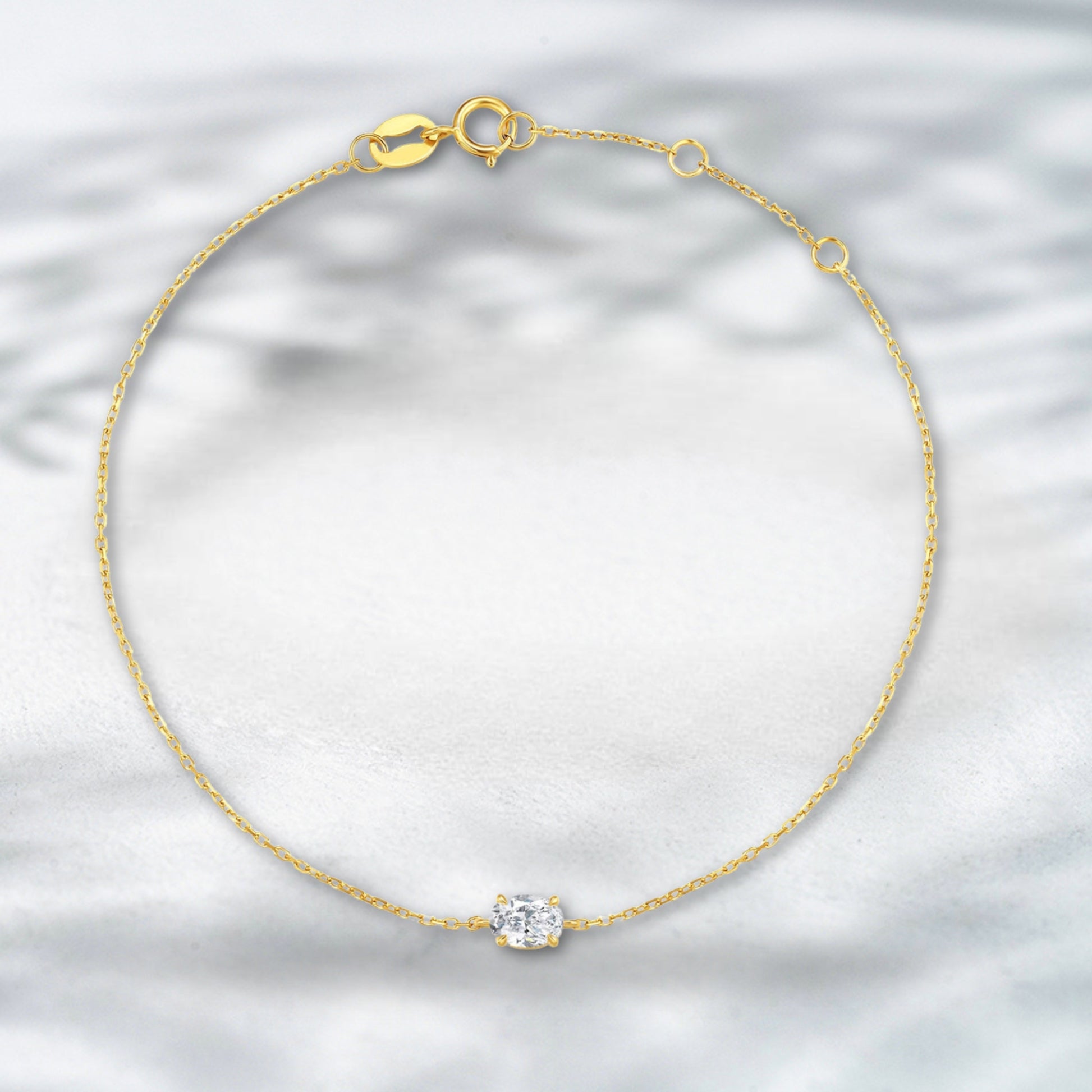 Gold bracelet with a diamond on a light gray background