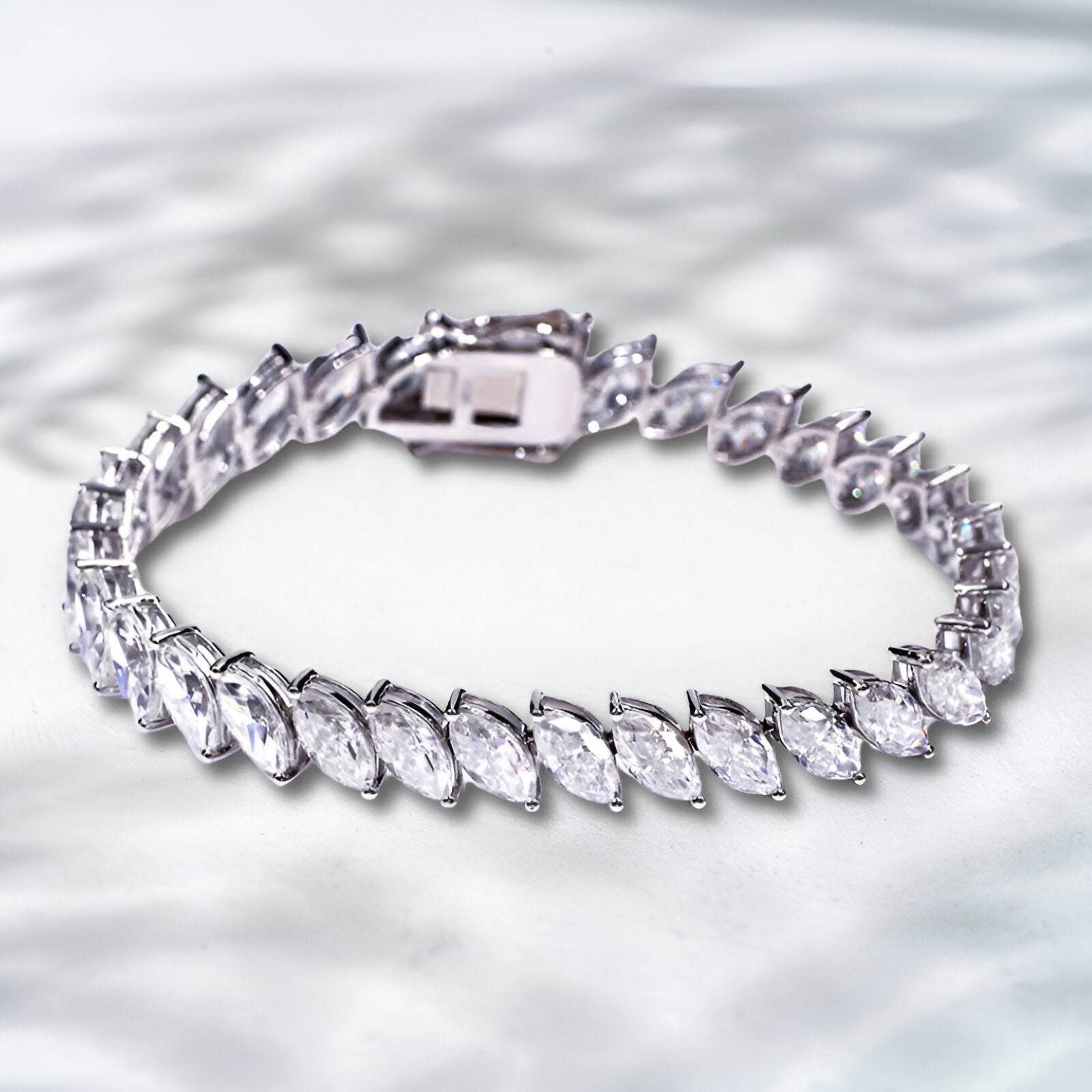 Silver bracelet with clear gemstones on a textured silver background