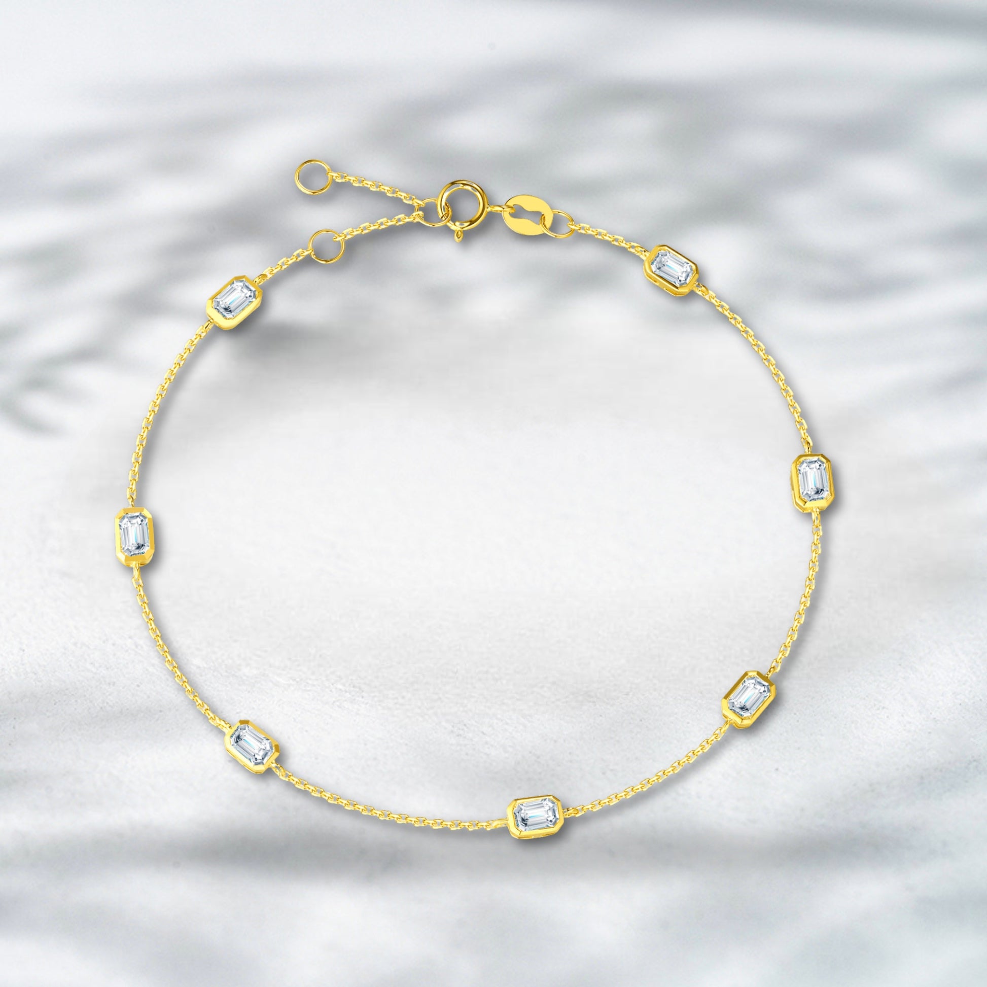 Gold bracelet with diamond-like stones on a textured silver background