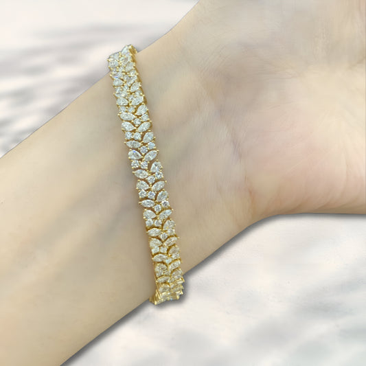 Gold bracelet with clear stones on a wrist against a neutral background