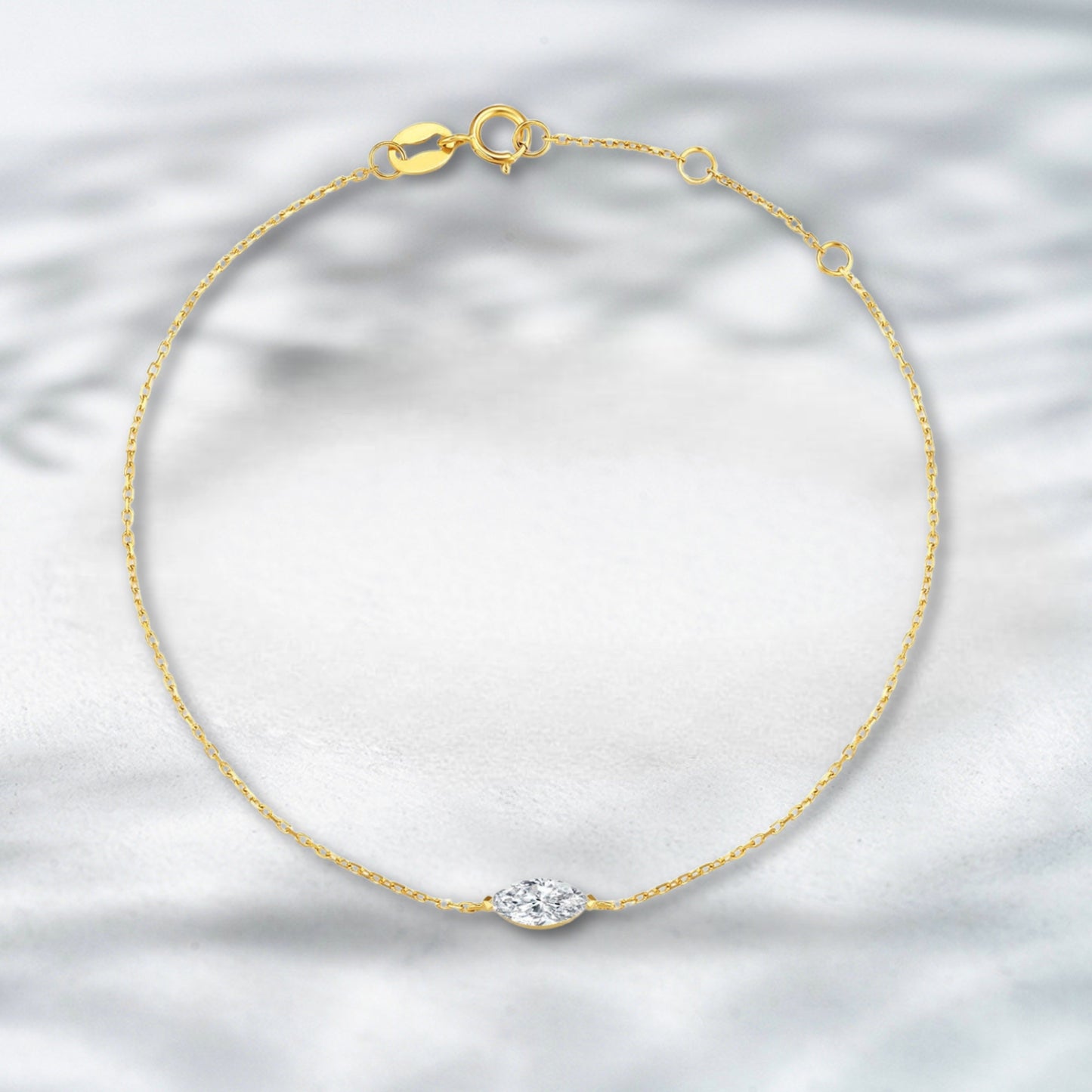 Gold bracelet with a diamond on a light gray background