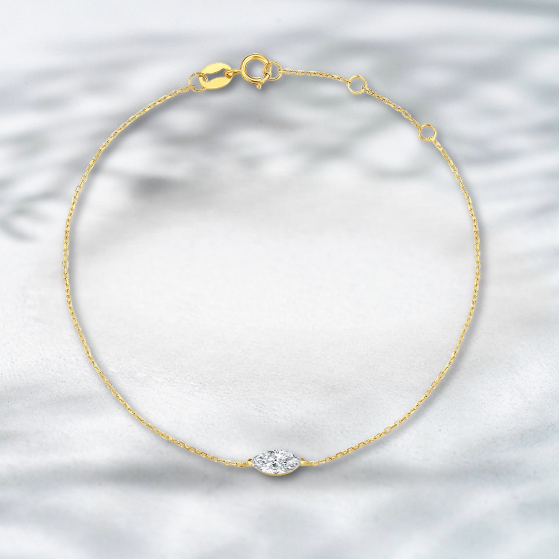 Gold bracelet with a diamond on a light gray background